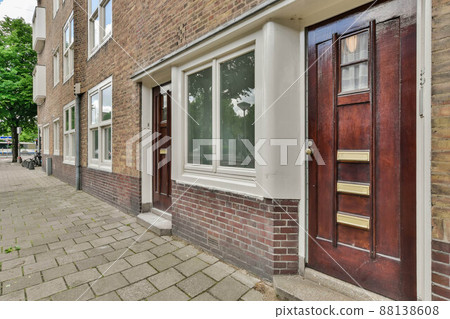 Facade of a residential brick house with doors and windows and sidewalks made of tiles Facade of a residential brick house with doors and windows and sidewalks made of tiles 88138608