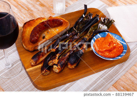 Appetizing calsot served with Romesco sauce and sausage butifarra 88139467