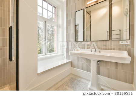 Bathroom with ceramic sink under the mirror and a small window in a modern house Bathroom with ceramic sink under the mirror and a small window in a modern house 88139531