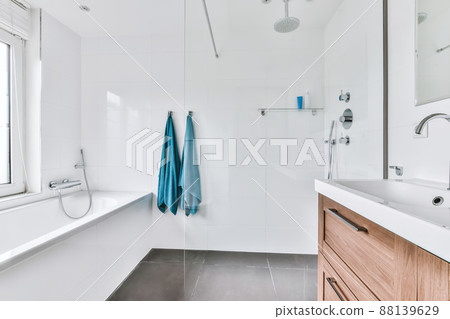 An amazing bathroom with snow-white tiles and a comfortable bathtub 88139629