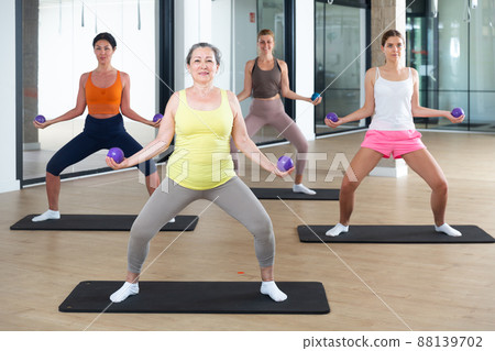 Women performing set of exercises with two small pilates balls 88139702