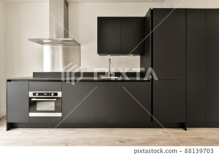 Corner kitchen of dark shade in minimalist style in a studio apartment 88139703