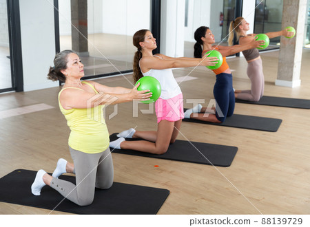 Women exercising with ball during group pilates class 88139729