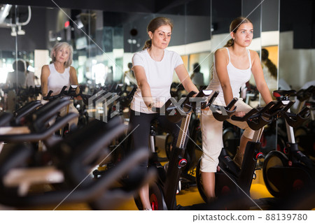 Young woman and her mother on bikes in gym 88139780