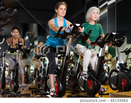 Women exercising on stationary bikes at gym 88139968