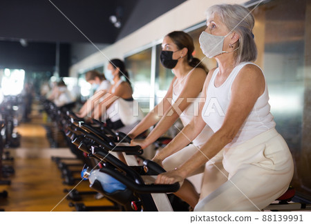 Adult woman in mask with fitness bike in gym Adult woman in mask with fitness bike in gym 88139991