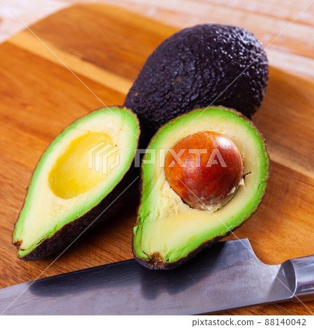 Fresh avocadoes and kitchen knife on cutting board 88140042