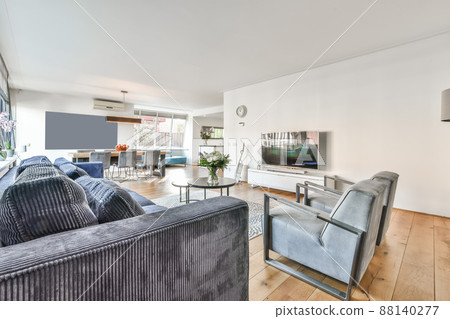 Bright spacious living room with a large sofa in front of the TV and a small rug in a modern apartment Bright spacious living room with a large sofa in front of the TV and a small rug in a modern apartment 88140277