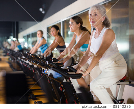 Elderly woman warming up on bike at gym Elderly woman warming up on bike at gym 88140286