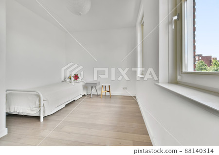 A small bedroom in a minimalist style with a simple bed and several windows A small bedroom in a minimalist style with a simple bed and several windows 88140314