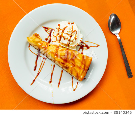 Slice of apple cake with caramel sauce and whipped cream 88140346