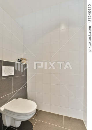 Toilet room lined with white and black tiles in a modern house 88140420