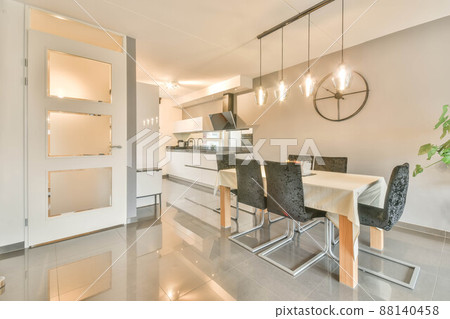 Spacious dining area combined with a kitchen with white furniture 88140458