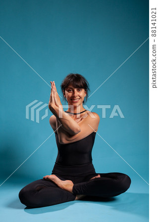 Portrait of smiling zen woman trainer standing in lotus position holding arms in crossed position practicing spiritual meditation. Athletic person working at healthy lifestyle stretching body muscles 88141021