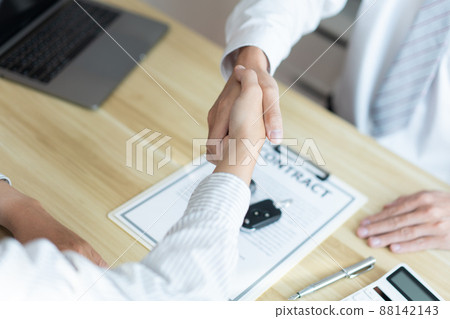 Insurance concept the car broker shaking hand with his customer after finishing dealing the contract Insurance concept the car broker shaking hand with his customer after finishing dealing the contract 88142143