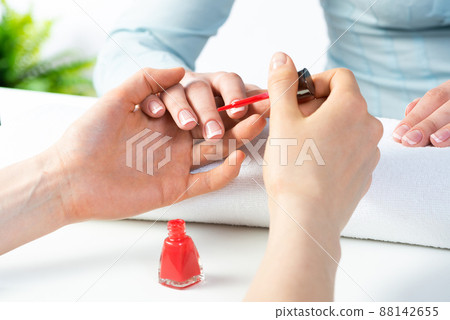 Woman receiving manicure by nail beautician 88142655