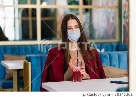 Close up portrait of a caucasian female wearing a medical mask and standing in the street and cafe Close up portrait of a caucasian female wearing a medical mask and standing in the street and cafe 88145301