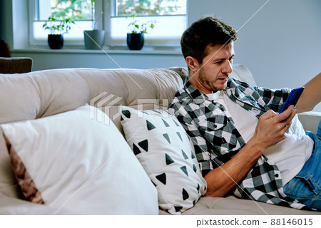 Man using smartphone while resting on sofa. Online social media 88146015