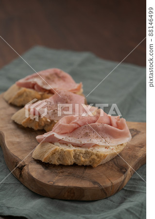 Toassted baguette slices with prosciutto cotto and cream cheese on olive wood board Toassted baguette slices with prosciutto cotto and cream cheese on olive wood board 88146499