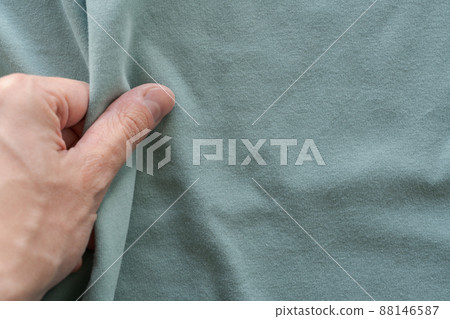 Closeup man hand touch teal cotton fabric for clothes 88146587