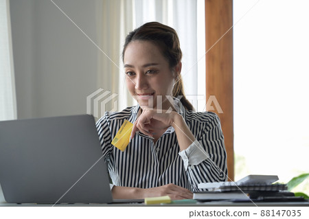 Attractive woman holding credit card and using internet banking service, paying bills online on computer laptop. 88147035