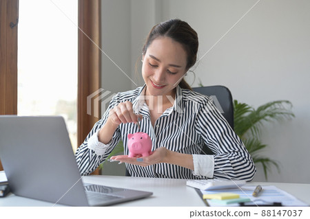 Attractive young woman putting coin into piggy bank. Saving money, banking, economy concept. 88147037