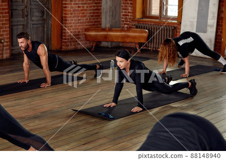 group of athletic young people in sportswear doing push ups or plank at the gym, group fitness concept group of athletic young people in sportswear doing push ups or plank at the gym, group fitness concept 88148940