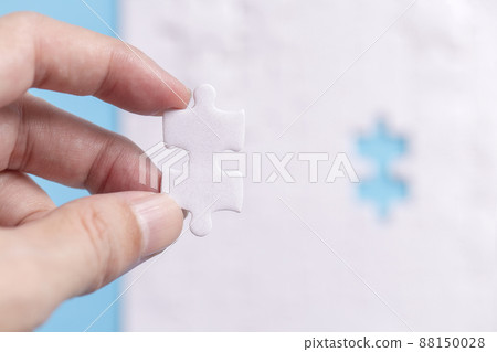 hand holding one part out of group with jigsaw puzzle on blue background, Working concepts separated from groups 88150028