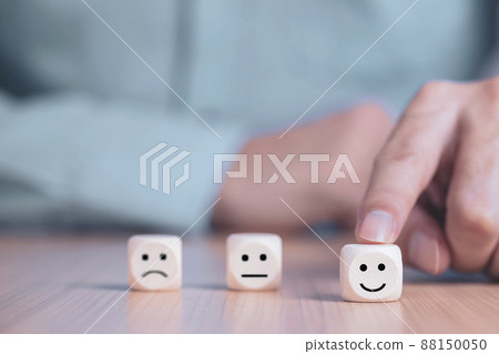 Businessman chooses a smile emoticon icons face happy symbol on wooden block , Services and Customer satisfaction survey concept Businessman chooses a smile emoticon icons face happy symbol on wooden block , Services and Customer satisfaction survey concept 88150050
