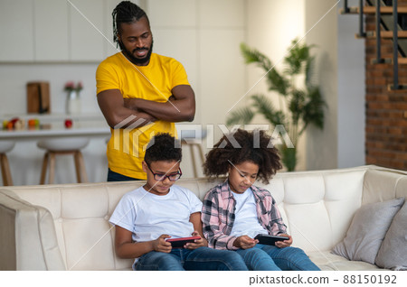 Man watching children looking at smartphones Man watching children looking at smartphones 88150192