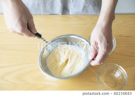 Image of mixing eggs and milk in a stainless steel bowl 88150683
