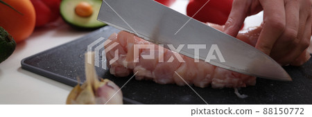 Female hands cut meat with a knife, vegetables on the table 88150772