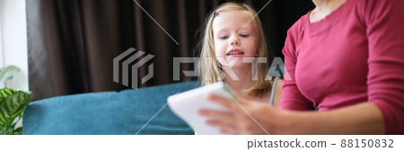 Mom sits on the couch and teaches her daughter to draw Mom sits on the couch and teaches her daughter to draw 88150832