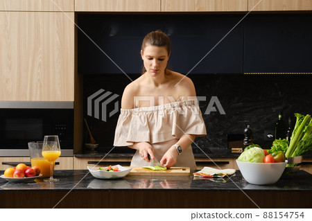 Pregnant woman woman cuts a celery stalk into pieces 88154754