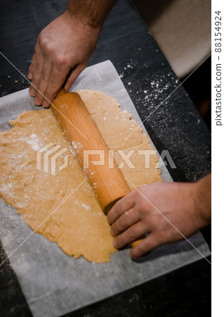 male hands roll gingerbread dough with a wooden rolling pin, close-up male hands roll gingerbread dough with a wooden rolling pin, close-up 88154924
