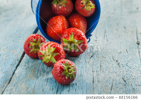 Fresh ripe strawberries in a blue bucket on a wooden background 88156166