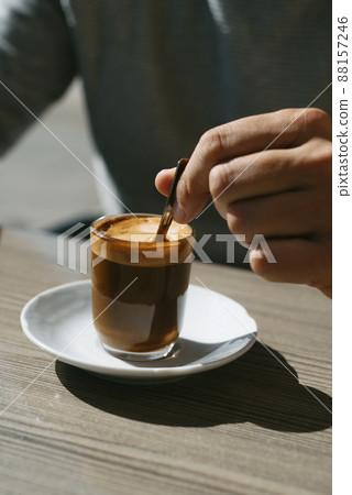 man stirring his machiatto with a coffee spoon 88157246