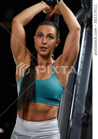 strong-willed young woman fitness coach engaged with a barbell in the simulator in the gym. Concept of strong muscles and taut figure 88157611