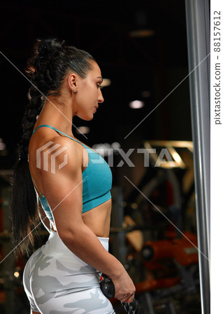 strong-willed young woman fitness coach engaged with a barbell in the simulator in the gym. Concept of strong muscles and taut figure 88157612