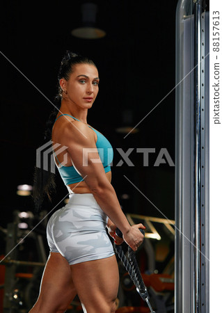 strong-willed young woman fitness coach engaged with a barbell in the simulator in the gym. Concept of strong muscles and taut figure 88157613