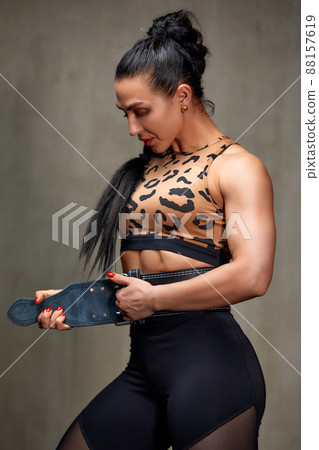 Attractive Young Woman Standing Strong In The Gym And Flexing Muscles - Beautiful Athletic Fitness Model Posing After Exercises. Attractive Young Woman Standing Strong In The Gym And Flexing Muscles - Beautiful Athletic Fitness Model Posing After Exercises. 88157619
