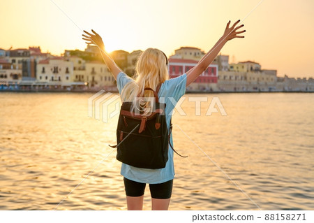 Happy blonde female with backpack on sea promenade, back view 88158271