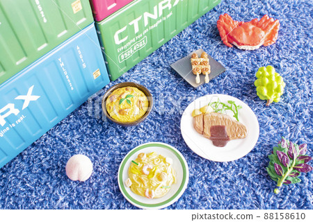 A container and lots of food miniatures placed on a blue towel 88158610