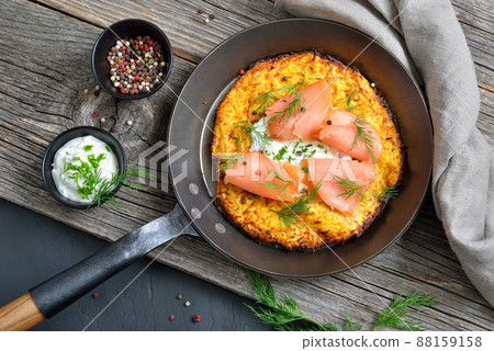 Large crispy potato pancake with smoked salmon and sour cream with fresh green herbs 88159158