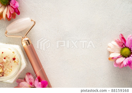 Pink quartz face roller with aroma candle, and flower on grey background. Minimal beauty flatlay with copy space Pink quartz face roller with aroma candle, and flower on grey background. Minimal beauty flatlay with copy space 88159168