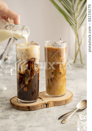 Iced coffee in glass. Pouring milk in glass with coffee. Summer drink. 88159276