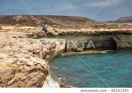 Woman standing over a cliff. Cape Greco peninsula park, Cyprus. 88161365