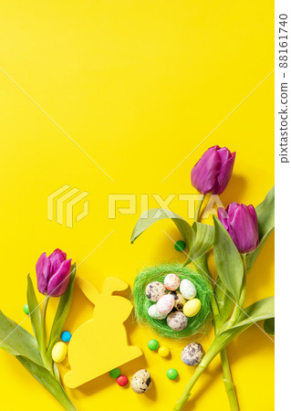 Colorful Easter background. Holiday greeting card with painted eggs, purple tulip. Top view flat lay. Copy space. Colorful Easter background. Holiday greeting card with painted eggs, purple tulip. Top view flat lay. Copy space. 88161740