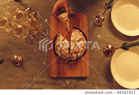 Female holding slice of freshly baked panettone cake above table served for festive dinner, photo in rustic style Female holding slice of freshly baked panettone cake above table served for festive dinner, photo in rustic style 88161921