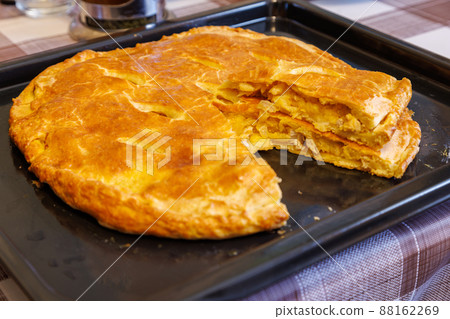 freshly baked domestic ossetian pie on a baking sheet with cutted piece over freshly baked domestic ossetian pie on a baking sheet with cutted piece over 88162269